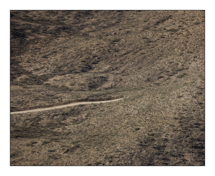  The border fence between Mexico (above) and the United States (below) stops abruptly as the Baboquivari Mountains rise out of the desert near the hard scrabble town of Sassabe that straddles the border in southern Arizona. The fence costs over one million dollars per mile and in areas where the terrain is especially harsh and dangerous to cross the construction halts. The consequence of this is that migrants are forced into areas where human life is incredibly difficult to sustain and they die.&nbsp; 