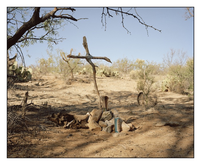 A cross made by a volunteer from the Tucson based charity ‘The Samaritans’ marks the grave of a Latin American migrant who died on the trail in the Tumacacori Mountains just west of Highway 19 and five miles from the border. There are many graves and shrines like this in the south western deserts. They are tended by American volunteers and migrants alike. Migrants will often forgo carrying precious life saving food and water so that they can carry candles and amulets to place on unmarked graves and shrines like this.&nbsp; 